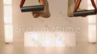 在瑜伽工作室吊床上伸展体操。 女孩在吊床上练习飞行瑜伽
